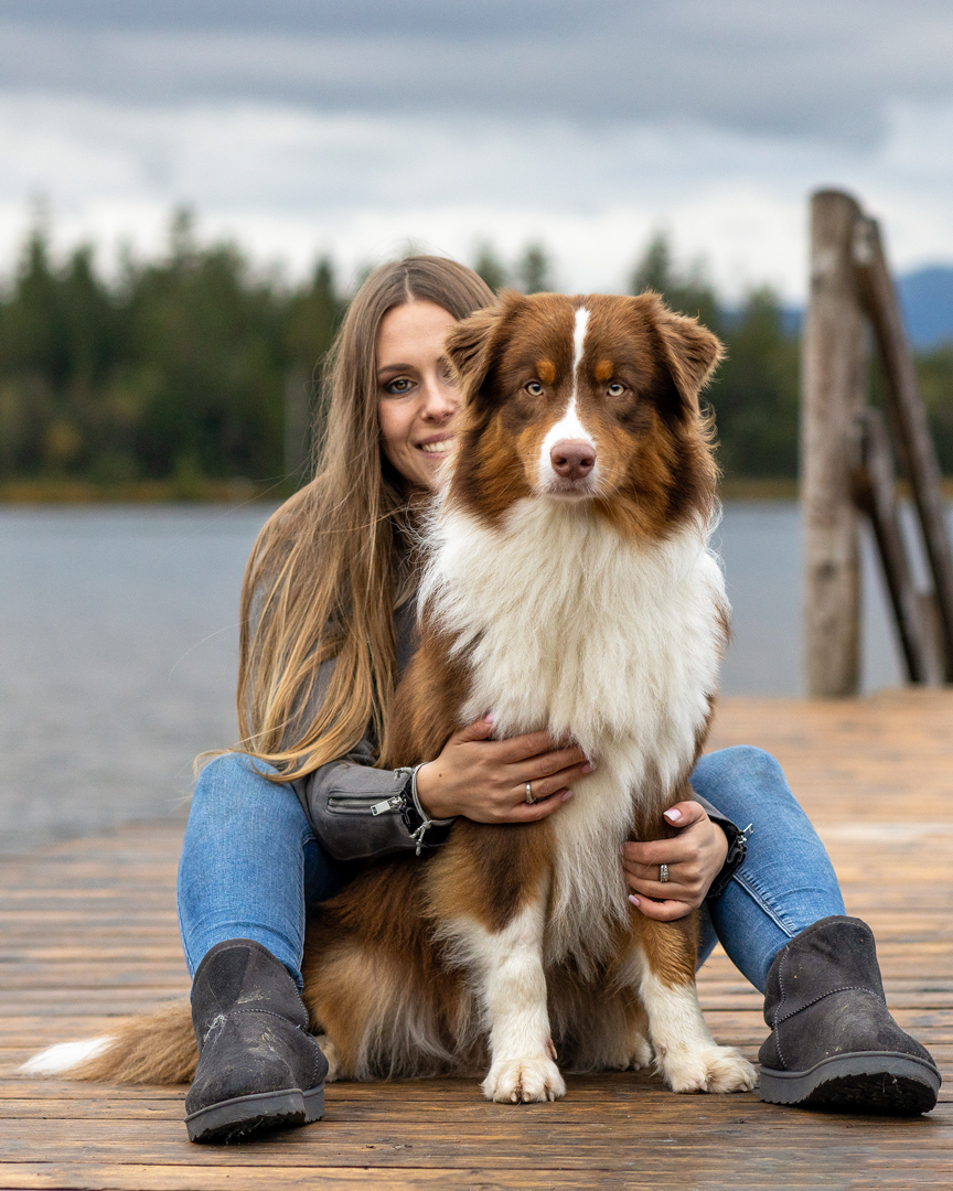 Tiershooting-Hunde-Hundeshooting Bild eines braunen Australian Shepherd Rüden mit seiner Besitzerin sitzen auf einem Steg